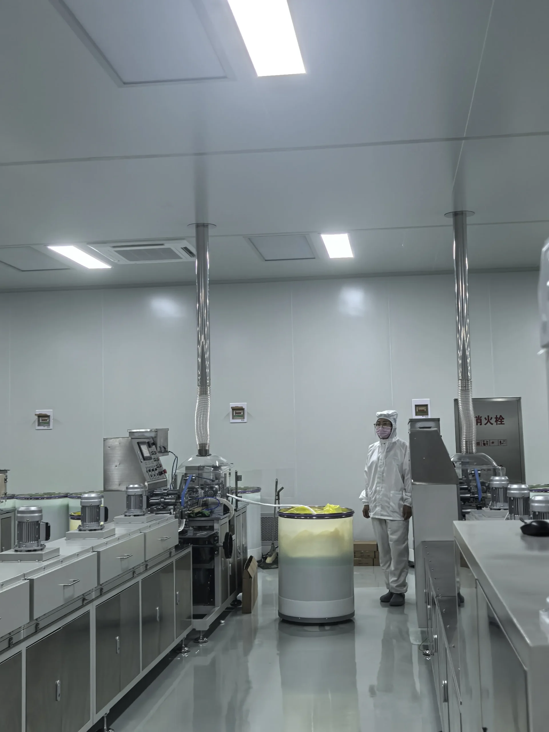 Operator wearing cleanroom clothing beside cotton swab production equipment